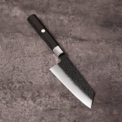 5 inch K-Bunka knife with kurouchi black blade and ebony octagonal handle on grey concrete