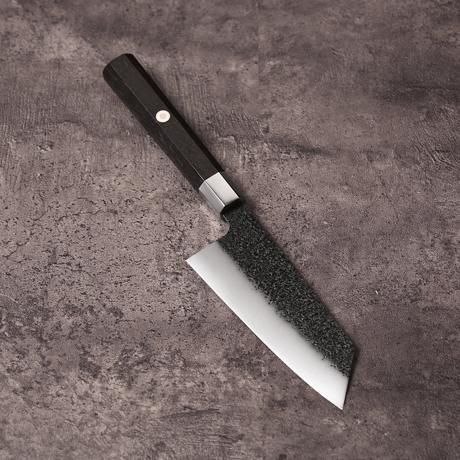 5 inch K-Bunka knife with kurouchi black blade and ebony octagonal handle on grey concrete