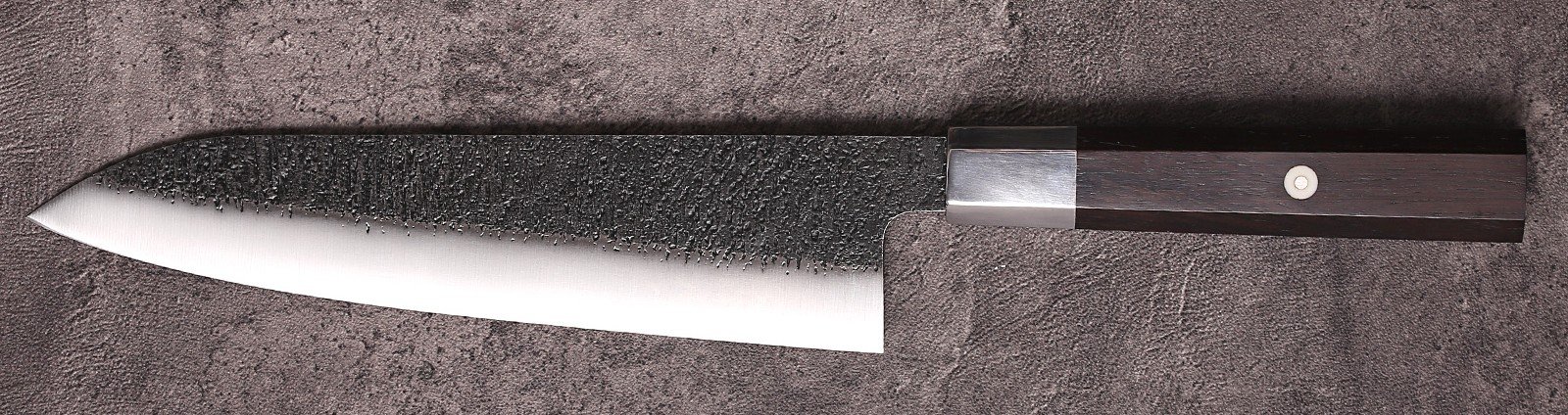 AUS-10 gyuto chef knife full profile on stone with kurouchi blade and ebony handle