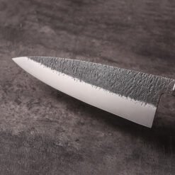Close-up of kurouchi textured finish and polished cutting bevel on AUS-10 steel blade