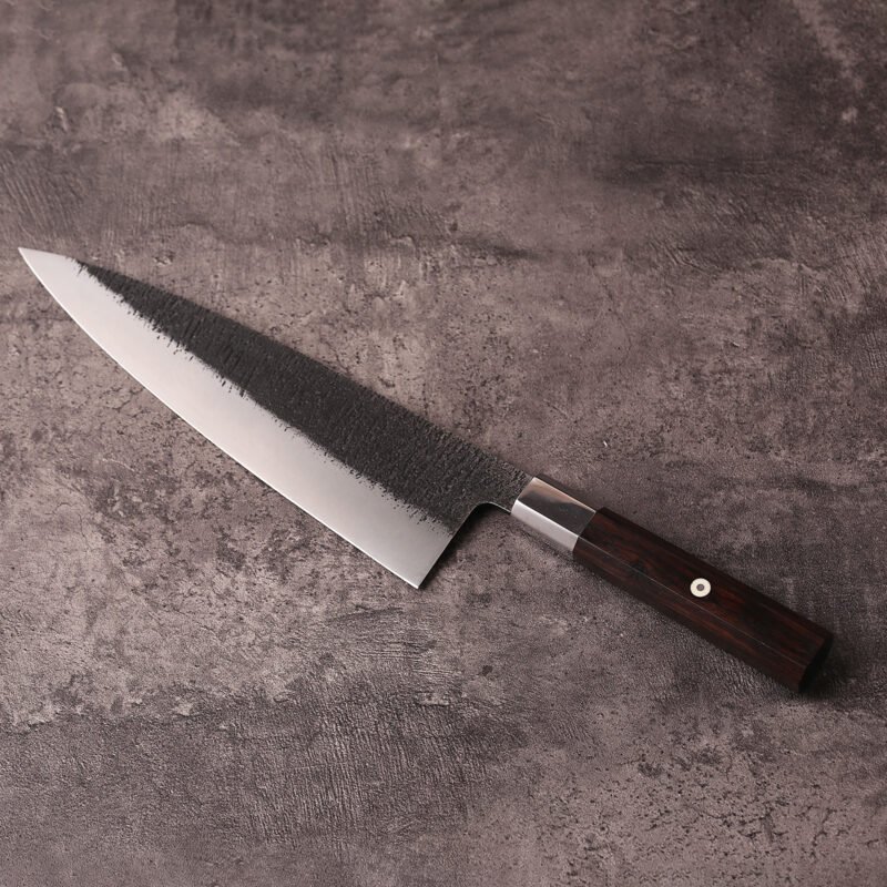 Japanese-style 240mm gyuto knife with black textured blade on stone surface