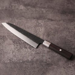 Monosteel AUS-10 gyuto knife on stone with polished edge and ebony octagonal handle