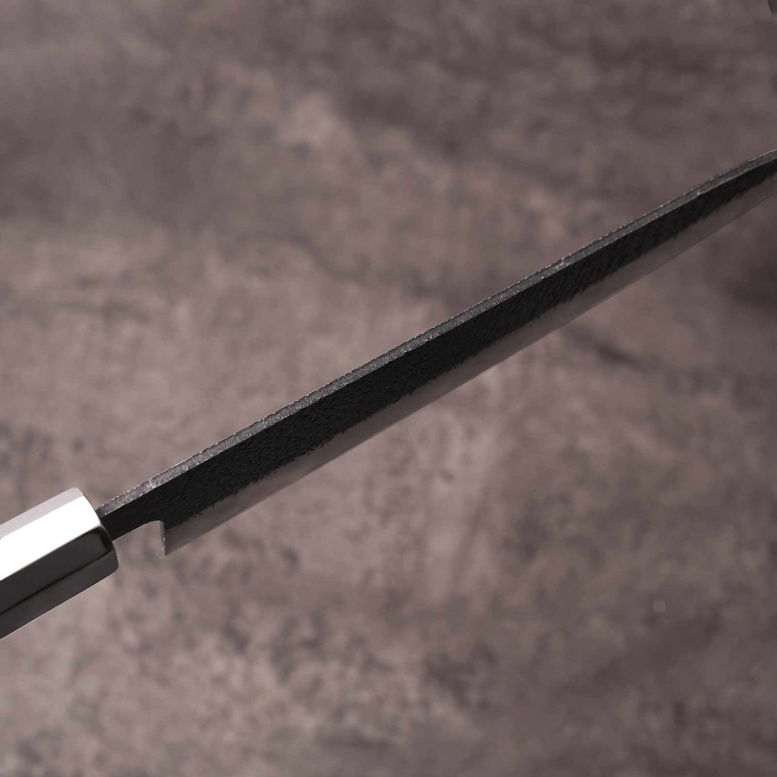 2.5mm spine of the AUS-10 santoku knife tapering forward from the stainless ferrule